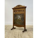 An Edwardian floral carved walnut fire screen, having a glazed oil on canvas panel depicting a