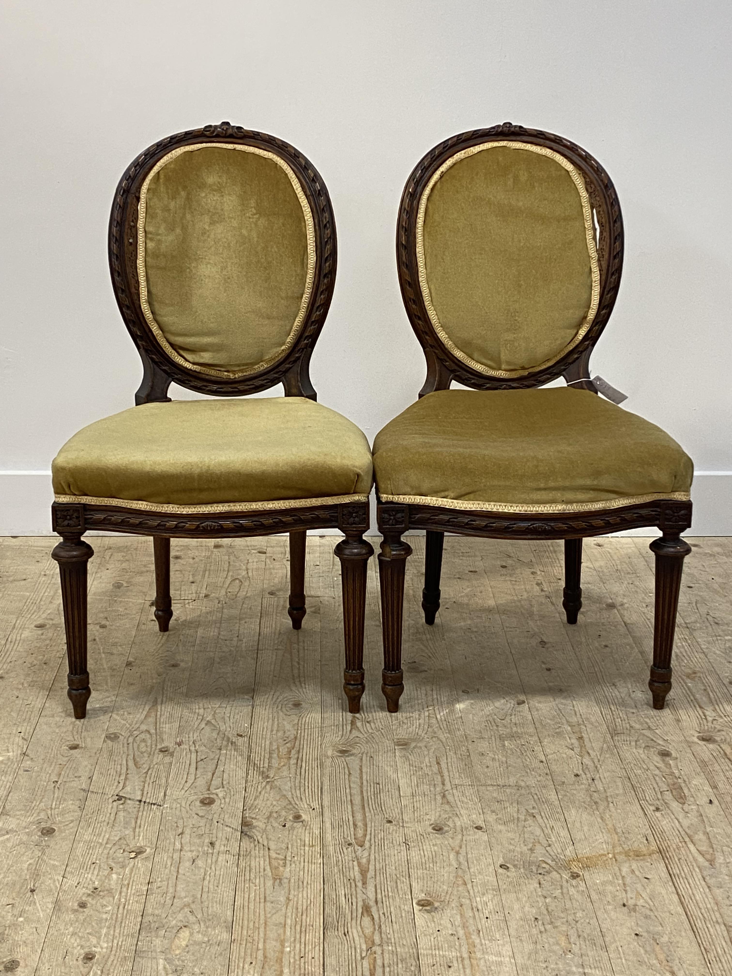 A pair of 19thc walnut side chairs, the oval back with spiral moulded show frame, over upholstered