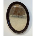 An Edwardian simulated rosewood composition oval wall hanging mirror, the frame with egg and dart