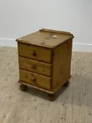A late 20th century polished pine three drawer bedside chest on bun supports and castors H63cm,
