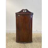 A Georgian mahogany bow front wall hanging corner cabinet, with swan neck pediment over dentil
