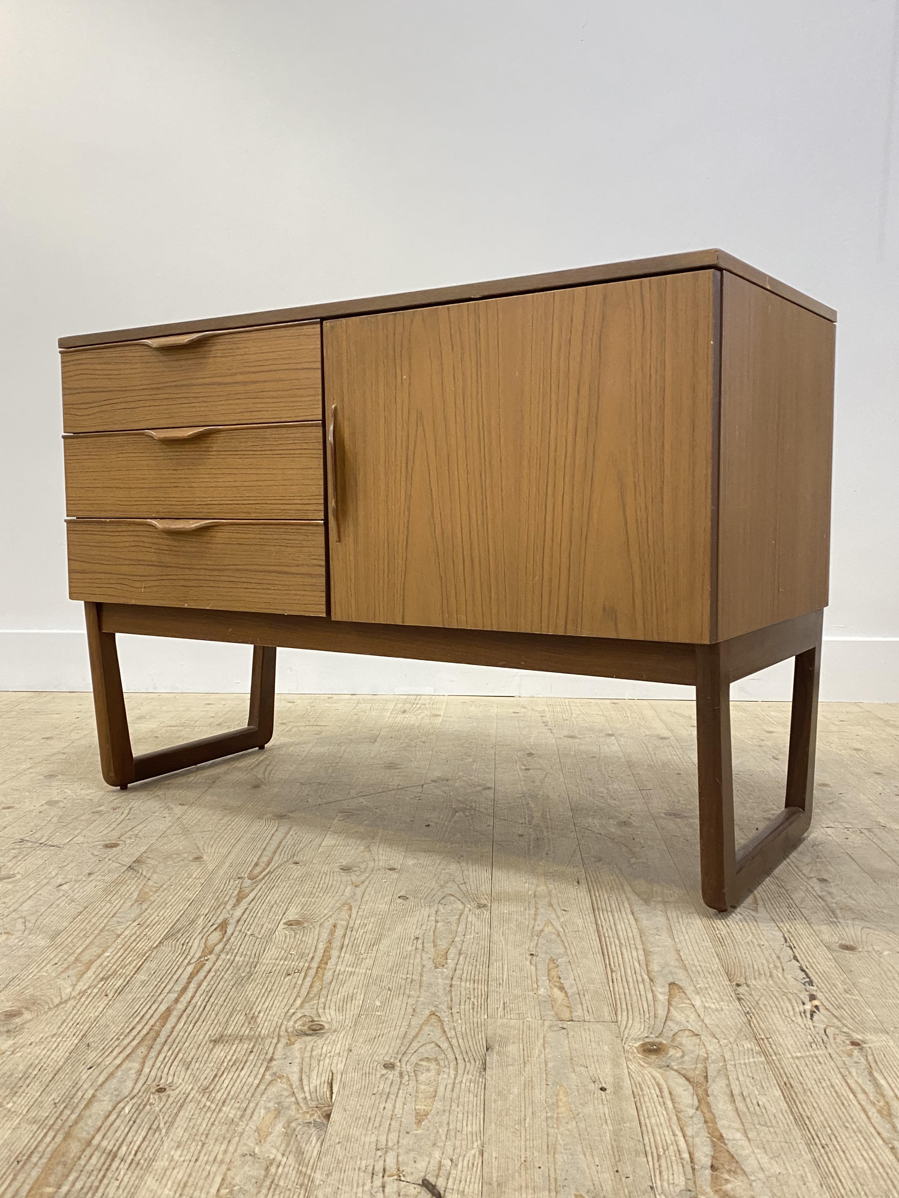 A mid century side cabinet, fitted with three drawers flanked by a cupboard door opening to a shelf,