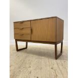 A mid century side cabinet, fitted with three drawers flanked by a cupboard door opening to a shelf,