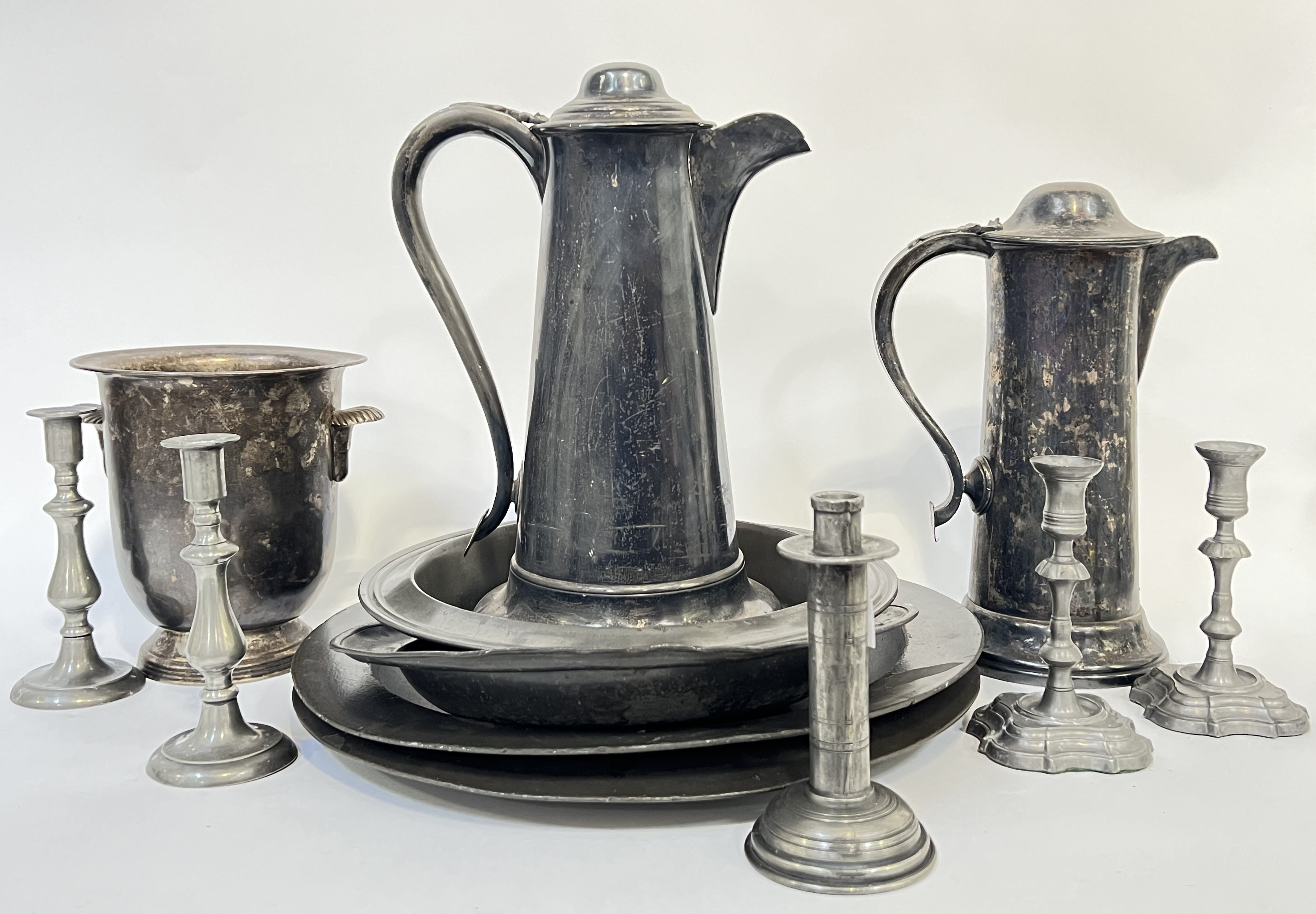 A group of pewter items comprising a Champagne bucket with scallop shell handles, four platters (