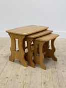 Ercol, a blonde elm nest of three tables, each with a shaped rectangular top raised on pierced panel