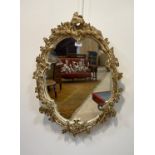 A parcel gilt and cream painted composition oval wall hanging mirror in the Rococo style 70cm x