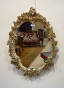 A parcel gilt and cream painted composition oval wall hanging mirror in the Rococo style 70cm x
