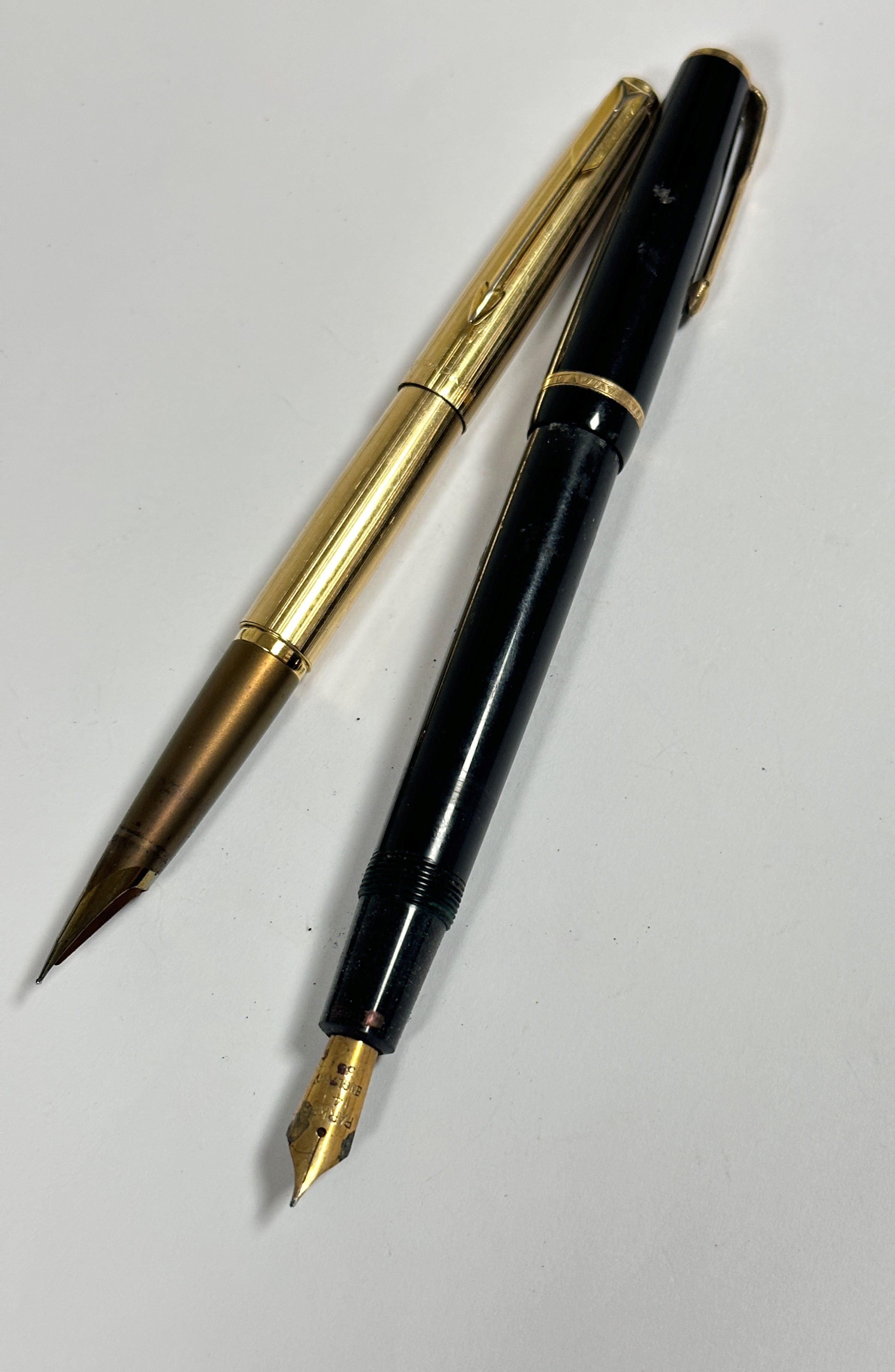 A modern gilt metal fountain pen, (including cap L: 13cm) and a vintage Parker black plastic