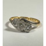 An 18ct gold and platinum set three stone scrolling graduated diamond ring mounted in rub over