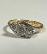 An 18ct gold and platinum set three stone scrolling graduated diamond ring mounted in rub over