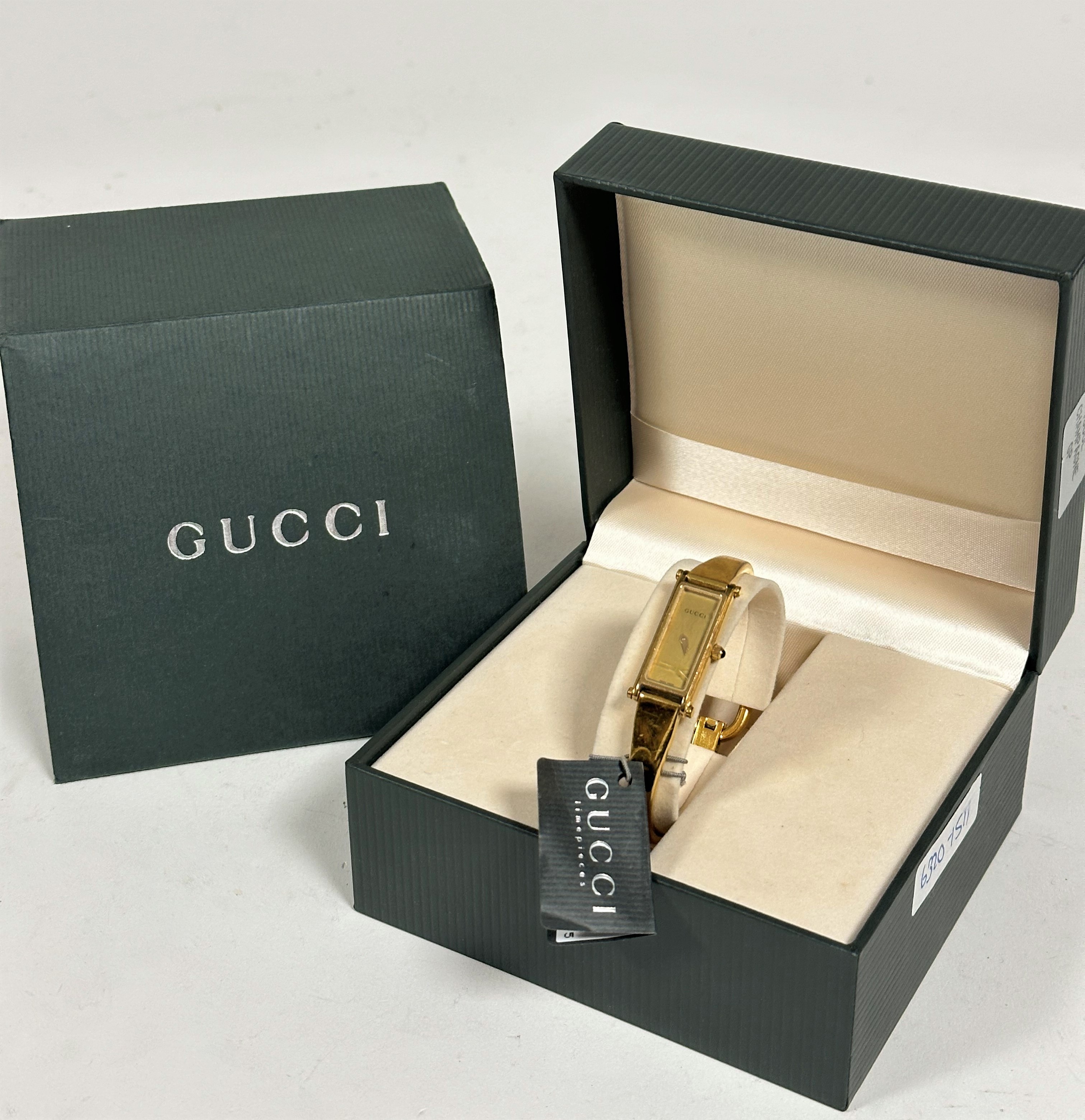 A Gucci gilt on stainless steel lady's quartz wristwatch with rectangular dial on metal stiff bangle