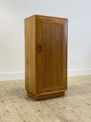 Ercol, An elm cabinet, late 20th century, the single door enclosing two adjustable shelves, raised