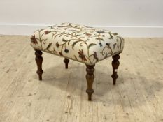 A Victorian stool, the seat covered in floral embroidered cotton, raised on turned supports,