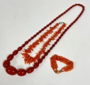 A rust coloured graduated amber bead necklace, (L: 37cm, largest bead 3cm x 2cm) (67.8g) a coral