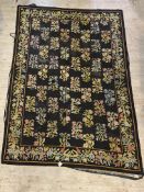 A needlepoint rug, the black field worked in a floral design and bordered 212cm x 304cm