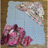 A group of three textiles comprising, a blue quilt with scalloped edge and pink floral sprays with a