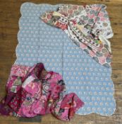 A group of three textiles comprising, a blue quilt with scalloped edge and pink floral sprays with a