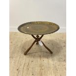 A chased and pierced brass tray table with scalloped edge raised on a folding hardwood base H52cm,