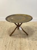 A chased and pierced brass tray table with scalloped edge raised on a folding hardwood base H52cm,