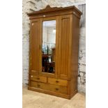 An Edwardian ash wardrobe, with floral incise carved pediment over mirror glazed door enclosing a