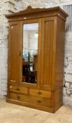 An Edwardian ash wardrobe, with floral incise carved pediment over mirror glazed door enclosing a