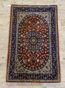 A hand knotted Iranian rug, the red field with scrolling arabesques within a deep blue border