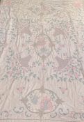 A 1930's/50s pink satinised bed cover decorated with an 18thc style embroidery of two figures with