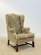 A mid 20th century wingback armchair of 18th century design, cotton upholstery worked in a floral