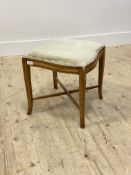 A satinwood corner stool, the top of serpentine outline upholstered in sage green velvet, raised