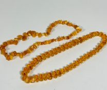 A strand of Lithuanian yolk coloured amber irregular shaped beads (31cm) and a clear faceted amber