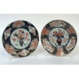 A pair of Japanese Imari porcelain plates, early 20th century, each centred by a flower-filled vase,