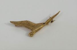 A vintage 9ct gold bird brooch, modelled as a gull in flight, the eye set with a red stone,