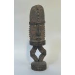 A carved wooden standing figure, Papua New Guinea, with cowrie shell eyes, elaborate headdress and