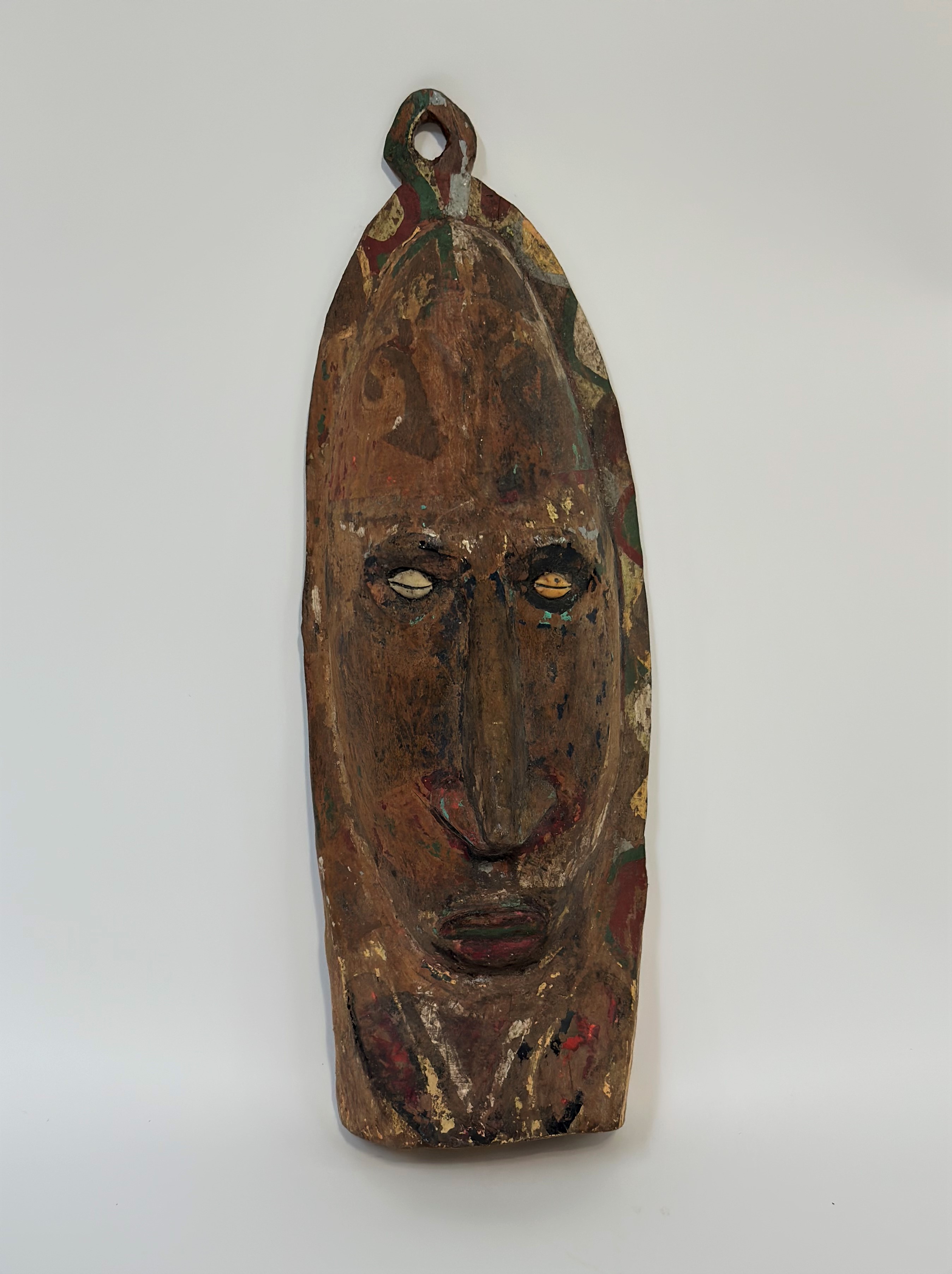 A painted wooden wall mask, Papua New Guinea, with cowrie shell eyes. Height 41cm