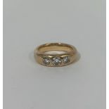 A three stone diamond ring, the three graduated round brilliant-cut stones gypsy-set in a 9ct yellow