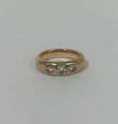 A three stone diamond ring, the three graduated round brilliant-cut stones gypsy-set in a 9ct yellow