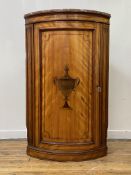 A 19th century ebony strung satinwood floor standing bow front corner cupboard, the top with rouge