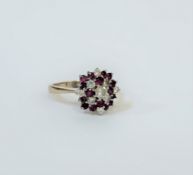 An 18ct white gold ruby and diamond cluster ring, the bombe setting formed of an arrangement of