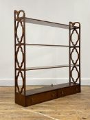 An Edwardian mahogany hanging wall shelf each tier united by pierced fret-carved panel end supports,
