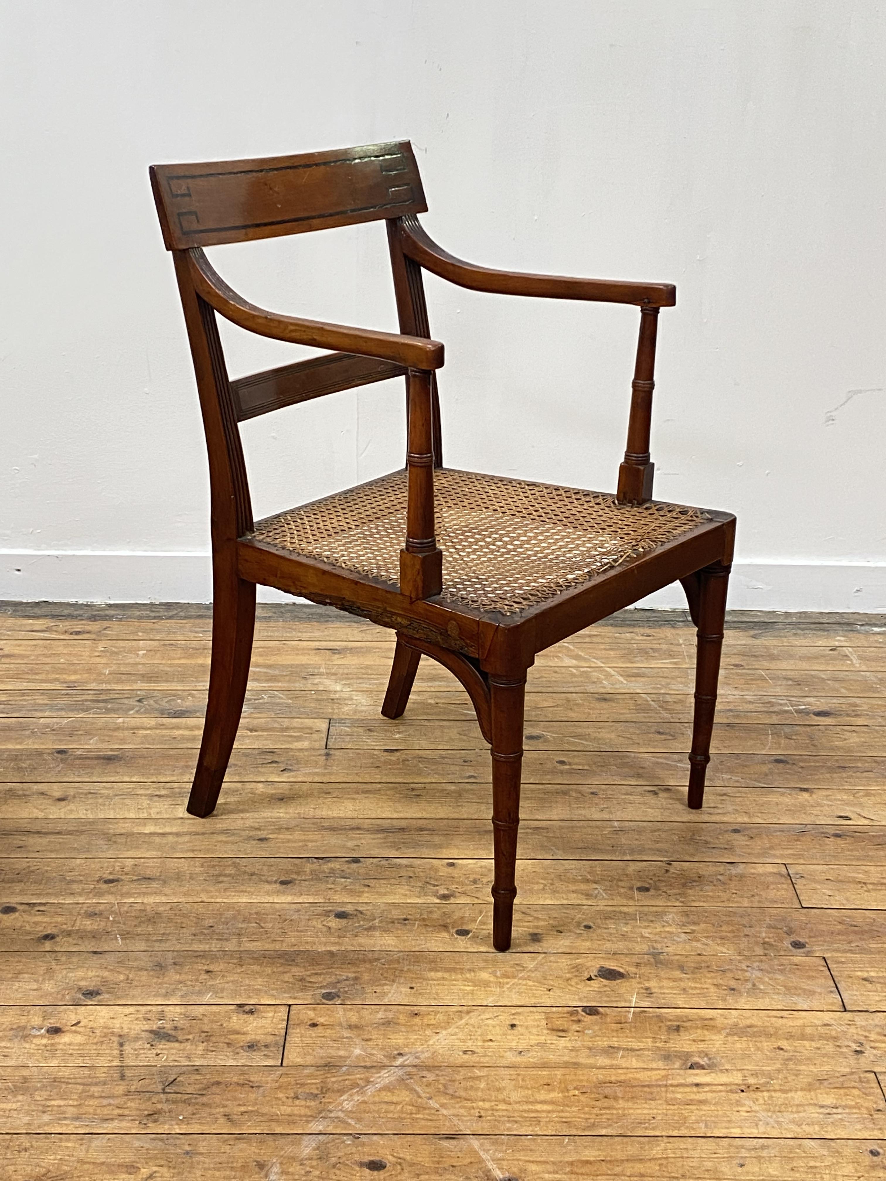 A Regency period yew wood elbow chair, the crest rail inlaid with ebony bands, above reeded open
