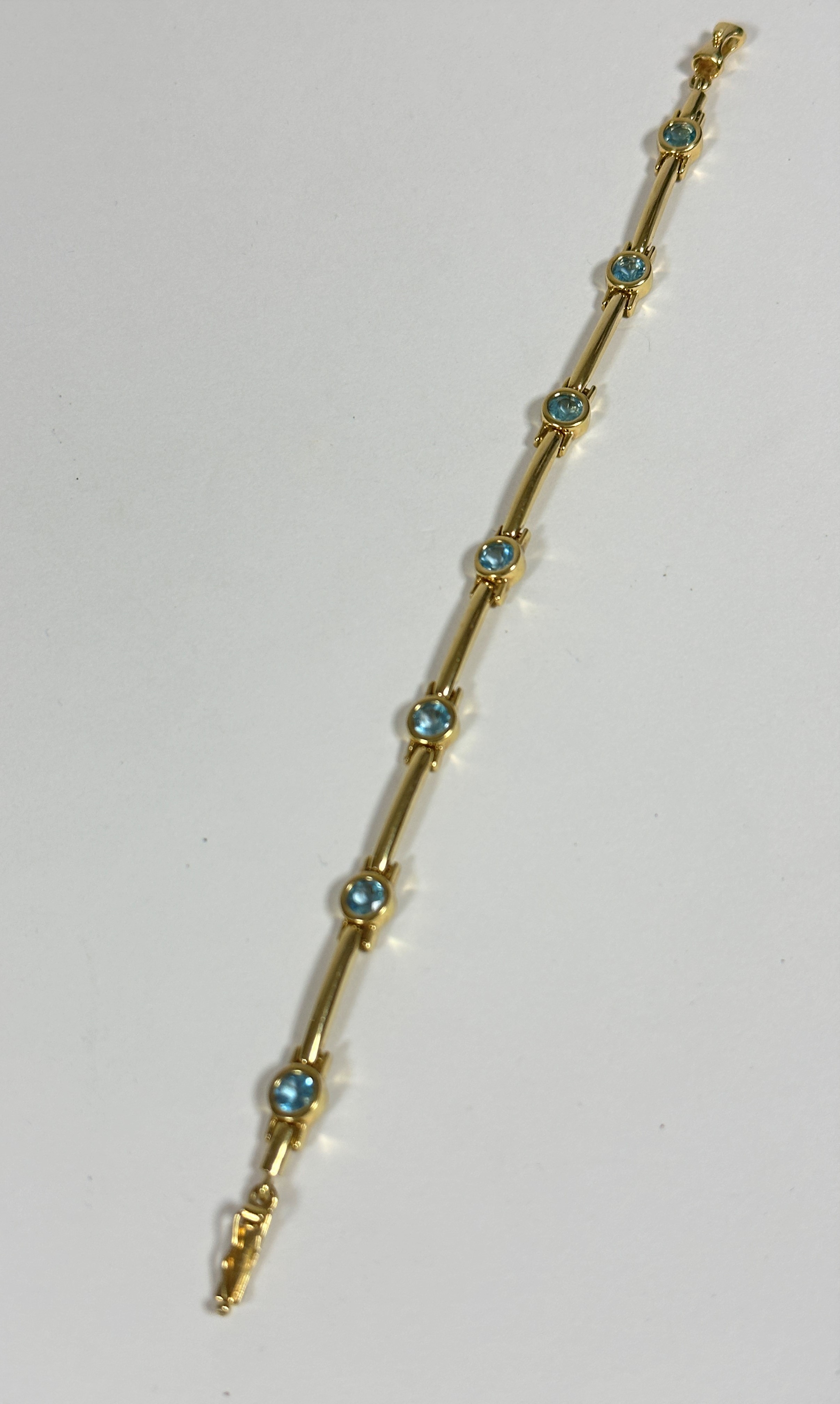 A 9ct gold link bracelet set seven zircons, complete with catch and safety pin (8.5cm) (10.04g),