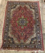 A Persian style rug, the busy red field with medallions and spandrels and bordered 294cm x 196cm