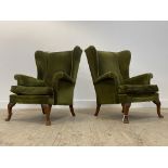 A pair of Parker Knoll wingback chairs in the Georgian taste, upholstered in green velvet, raised on