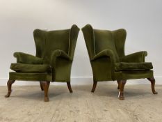 A pair of Parker Knoll wingback chairs in the Georgian taste, upholstered in green velvet, raised on