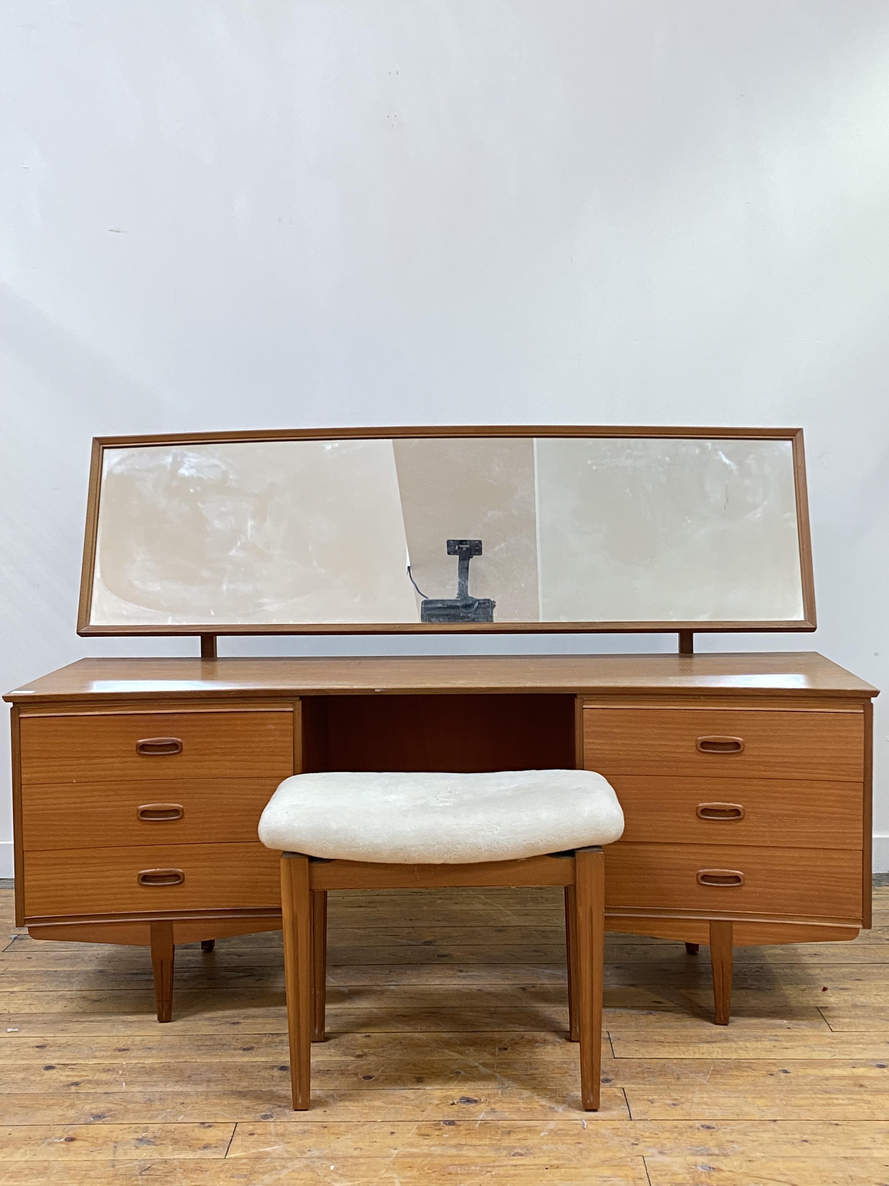 A mid century teak dressing table, circa 1960's, the arched rectangular mirror plate over a