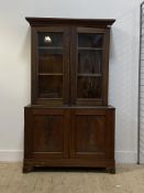 An Early 20th century mahogany and stained pine bookcase on cupboard, twin glazed doors enclosing