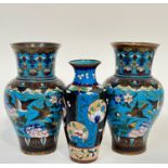 A pair of Meiji period Japanese cloisonne vases decorated with birds and flowers against a blue