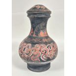 A pottery baluster jar and cover decorated with roman inspired scrolling design, on black ground (