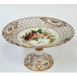 A gilt porcelain cake stand with enamelled rose decoration and pierced lattice design to the