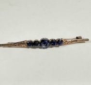 A yellow metal bar brooch set five coloured sapphires, mounted in claw setting, the centre